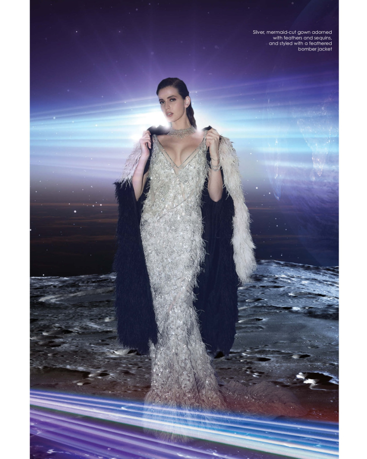 Silver, mermaid-cut gown adorned with feathers and sequins, and styled with a feathered bomber jacket