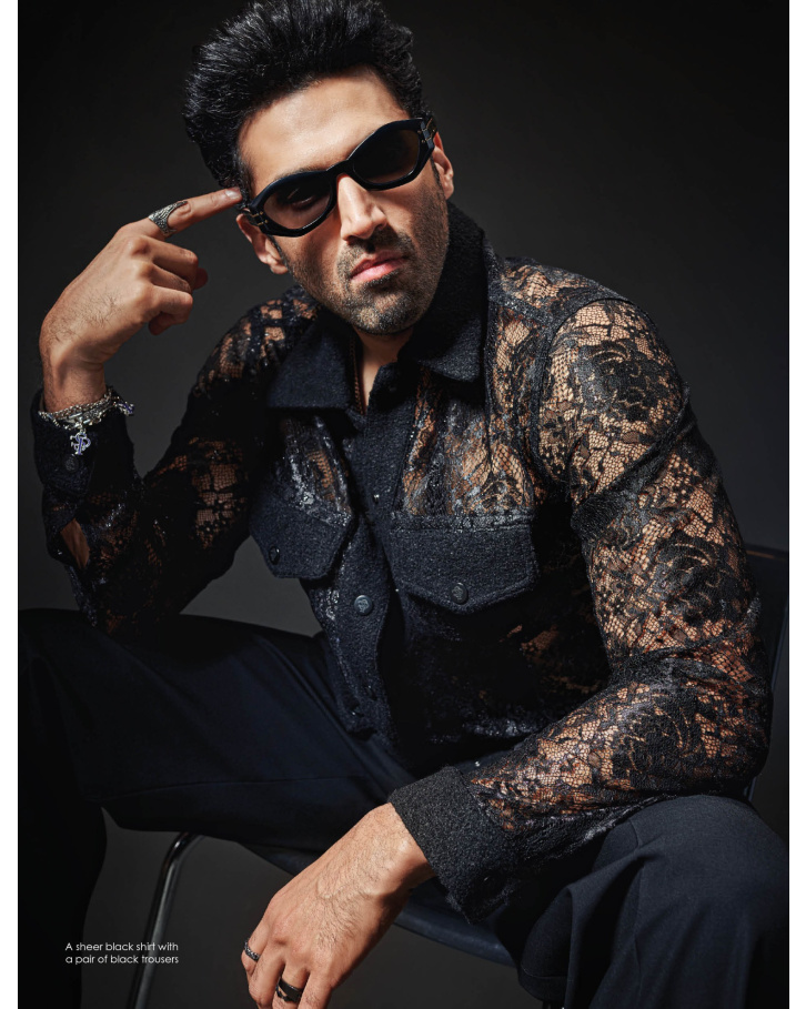 A sheer black shirt with a pair of black trousers